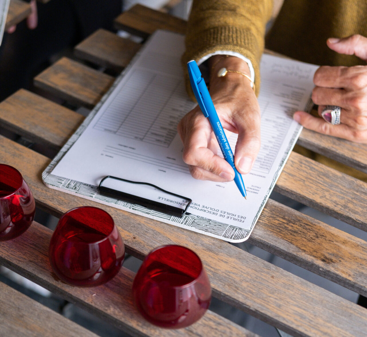 main qui rempli une feuille de profil pendant une dégustation d'huiles d'olive vierges